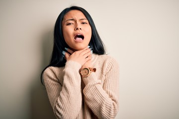 Young beautiful chinese woman wearing casual sweater over isolated white background shouting suffocate because painful strangle. Health problem. Asphyxiate and suicide concept.