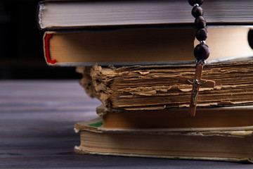 Wall Mural - Religious literature concept. Wooden cross with a rosary and stack of books.