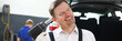 © H_Ko - Portrait of hardworking male engineer standing in modern car repair garage and posing with smile on camera. Optimistic worker checking automobile concept