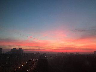 Beautiful red dawn of the sun in a big city metropolis with buildings and clouds. The view from the height