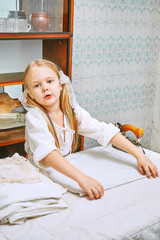 cute little girl ironing clothes in the kitchen. child assistant mistress