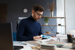 © YURII MASLAK - Architect working in office with color palette. Engineer select colors for building using color swatches, searching new ideas for construction project. Portrait of handsome bearded man at workplace.