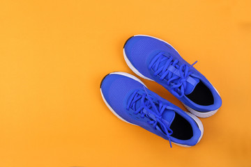 Wall Mural - Top view blue running shoes on orange pastel background