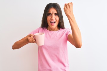 Wall Mural - Young beautiful woman drinking pink cup of coffee standing over isolated white background annoyed and frustrated shouting with anger, crazy and yelling with raised hand, anger concept