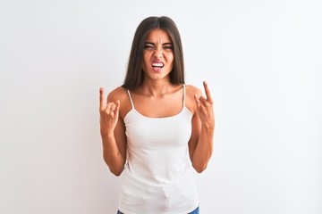 Wall Mural - Young beautiful woman wearing casual t-shirt standing over isolated white background shouting with crazy expression doing rock symbol with hands up. Music star. Heavy concept.