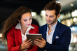 © Minerva Studio - Couple of business people using a tablet outdoor at night in a modern city setting
