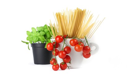 closeup of bowl with cherry tomatoes, spaghetti and basil jar on a white background