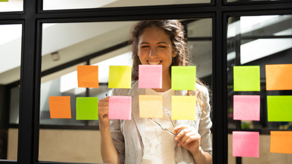 Wall Mural - smiling caucasian woman employee develop idea on sticky notes