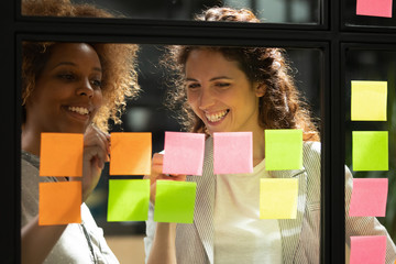Wall Mural - smiling multiracial women write on colorful sticky notes