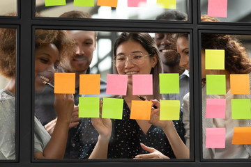 smiling multiethnic colleagues brainstorm using post it stickers