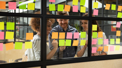 Wall Mural - smiling multiethnic colleagues brainstorm working with sticky notes