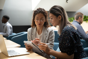 Focused millennial women discuss business plan in office