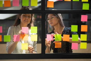 Wall Mural - multiethnic female employees brainstorm using sticky notes