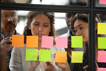 Wall Mural - Focused multiethnic colleagues write on colorful sticky notes