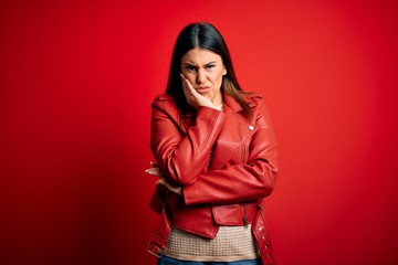 Sticker - Young beautiful woman wearing red leather jacket over isolated background thinking looking tired and bored with depression problems with crossed arms.