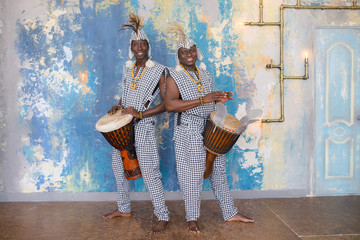 Wall Mural - A group of people in traditional african costumes playing jembe drums