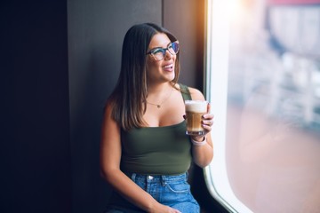 Canvas Print - Young beautiful woman on vacation smiling happy and confident. Standing on a deck of ship with smile on drinking coffee face doing a cruise