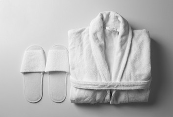 Poster - Clean folded bathrobe and slippers on white background, flat lay