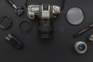 Poster - Photographer workplace with dslr camera system, camera cleaning kit, lens and camera accessory on dark black table background. Hobby travel photography concept. Flat lay top view copy space.