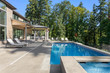 © bmak - Luxury home exterior and pool on sunny day with blue sky