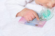 Hand of little baby infant boy point with finger to French European resident permit Titre de sejour and pacifier