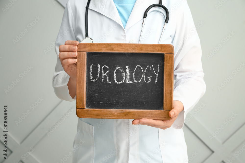 Doctor holding chalkboard with text UROLOGY on grey background