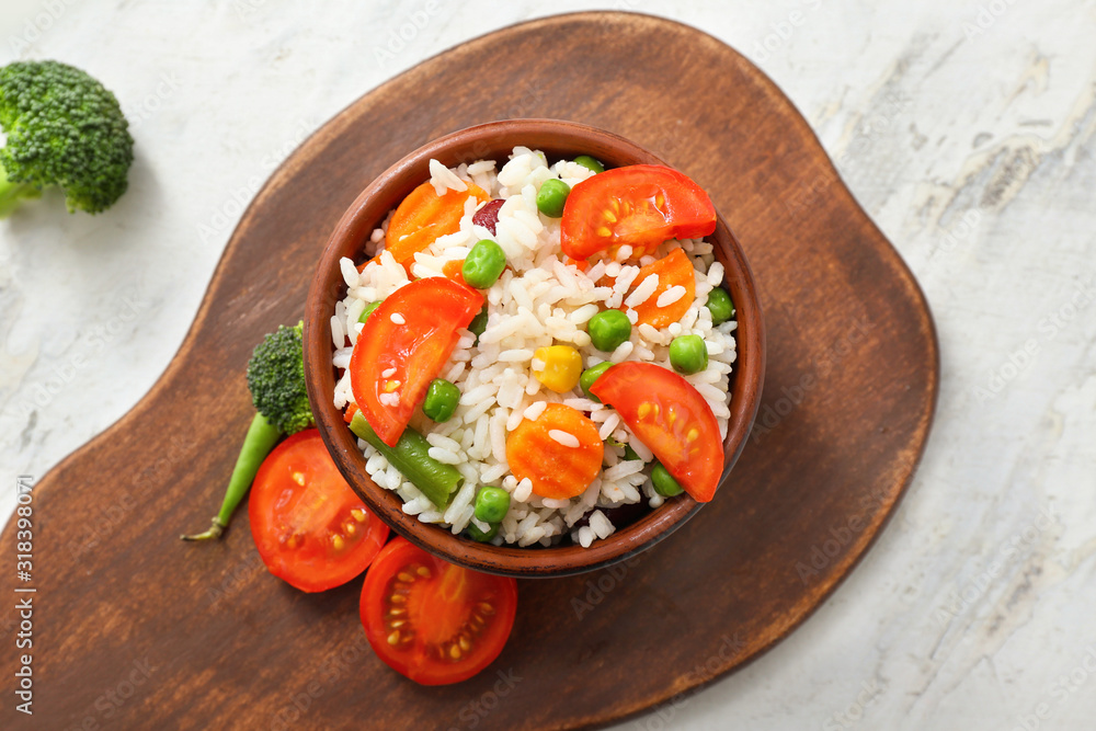 Boiled rice with vegetables in bowl on table