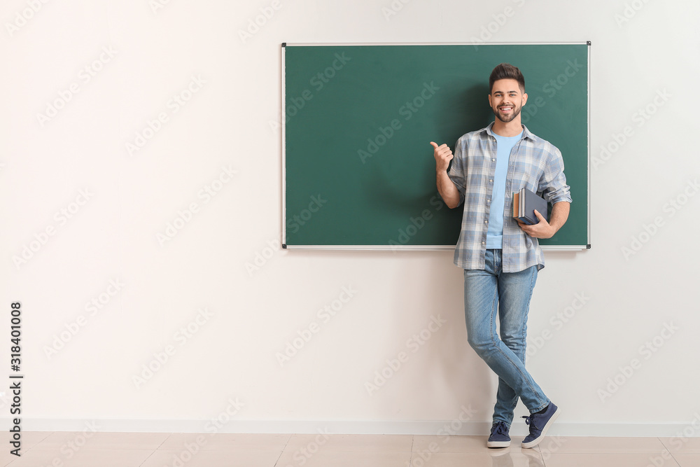 Male teacher near blackboard in classroom