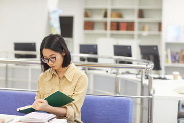 Wall Mural - Portrait of Asian young woman studying in college library modern interior in background, copy space