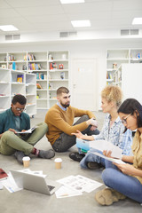 Wall Mural - Full length view at multi-ethnic group of students sitting on floor in library and discussing project, copy space