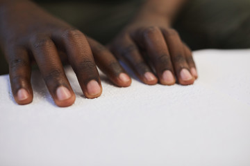 Wall Mural - Close up of unrecognizable blind African man reading braille book while studying in school, copy space