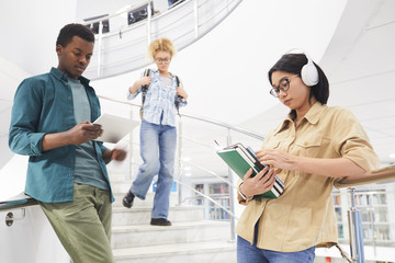Wall Mural - Multi-ethnic group of students posing by spiral stairs in modern college interior, copy space