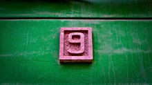Number 9, Nine, Sandstone Relief Digit On A Vivid Green Wall Background.