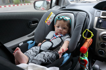 cute baby boy sitting on car seat safety belt lock protection for drive road trip travel in summer day