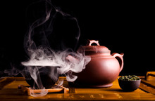 Chinese Tea Ceremony. Ceramic Tea Pot And Cups With The Famous Chinese Oolong Tea Tieguanyin  With Vapour On A Black Background.