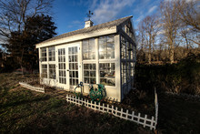 Beautiful Exterior Of A White Victorian Style Custom Built Greenhouse In A Winter Garden