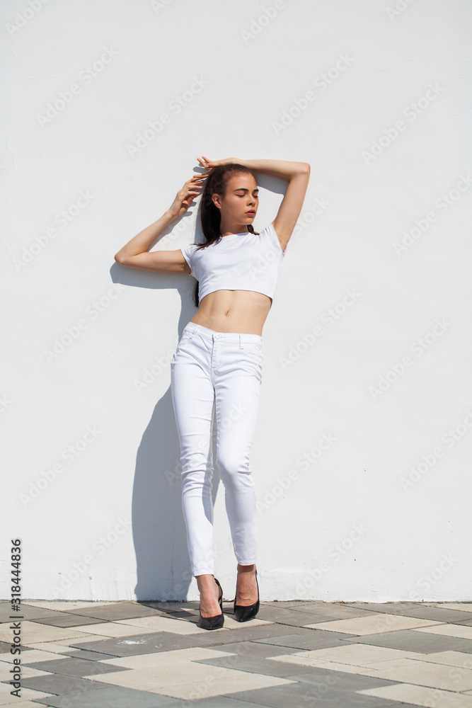Model tests. Young beautiful brunette model posing against a white wall - obrazy, fototapety, plakaty 