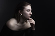 © Roman Kornev - Portrait in the photo Studio of a brown-haired girl, on a black background in black clothes with open shoulders. Short hair.