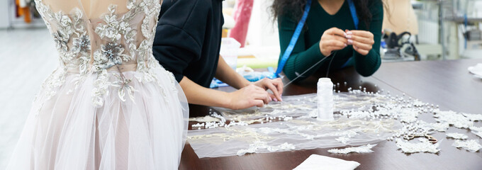 Mannequin with a wedding dress is in the tailor's shop. Dressmaker working in atelier.