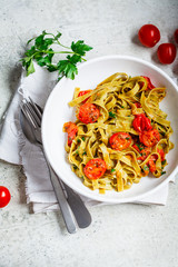 Poster - Green spinach pasta with tomatoes and herbs, top view. Healthy vegan food concept.