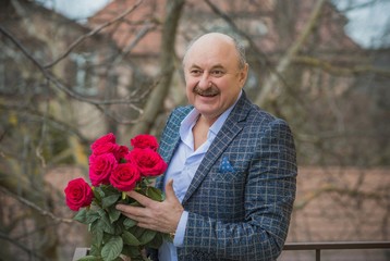 Older happy Senior man with a bouquet of flowers waiting on a date. Mature people lifestyle 