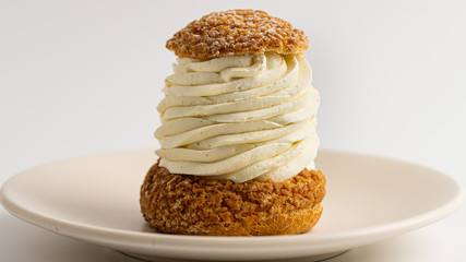 French dessert choux with whipped chocolate creme on a beige plate. White background