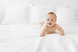 © Lisa Tichané - Happy baby lying on belly on white bed