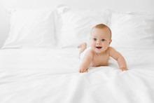 Happy Baby Lying On Belly On White Bed