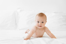 Funny Baby Lying On Belly On White Bed