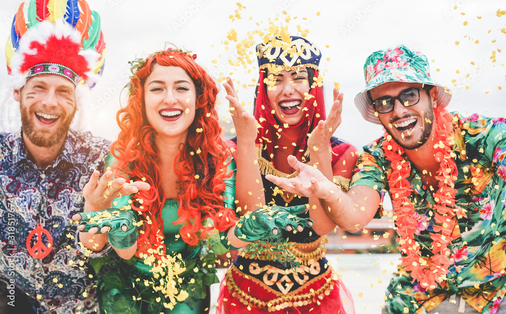 Happy dressed people celebrating at carnival party throwing confetti - Young friends having fun together at fest event - Youth, hangout, festive and happiness concept - Focus on left couple hands - obrazy, fototapety, plakaty 