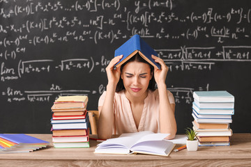 Wall Mural - Tired female teacher at table in classroom