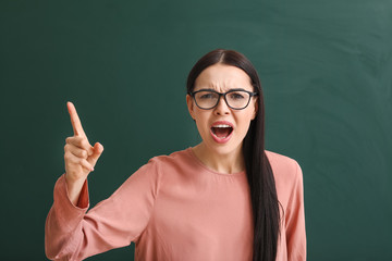 Poster - Angry female teacher near blackboard in classroom