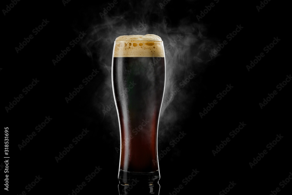 Cold pilsner beer glass with black porter beer inside covered with drops and froth evaporating on black background. - obrazy, fototapety, plakaty 