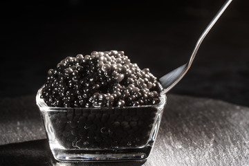 spoon of black caviar close-up in a heap of black caviar